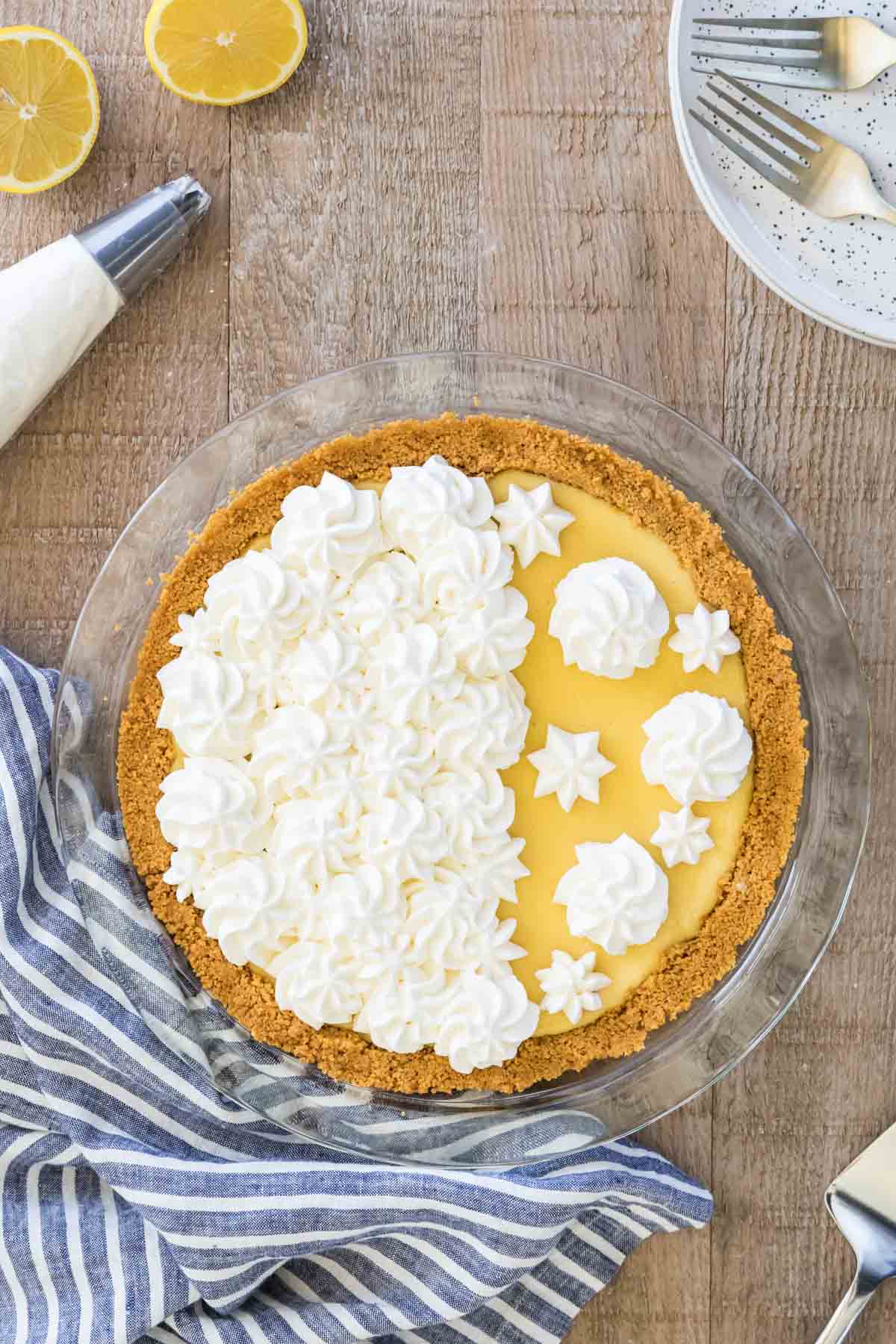Lemon pie in a glass pie plate decorated with whipped cream.
