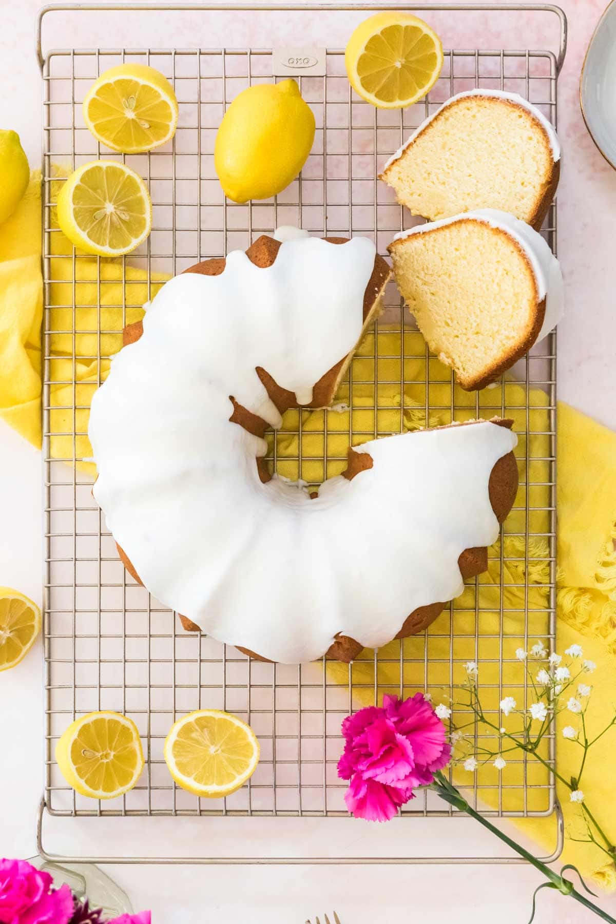 Overhead shot of lemon pound cake on a cooling rack with two pieces cut out and surrounded by cut lemons.
