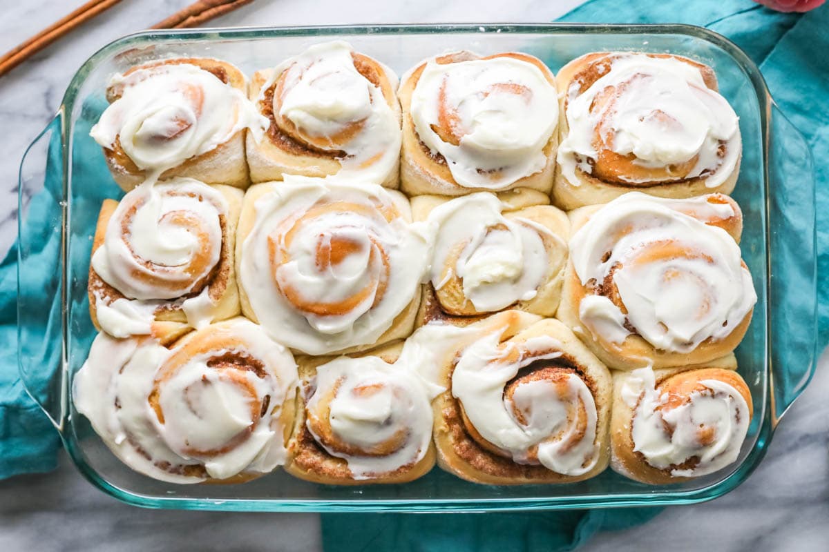 Overhead view of a glass pan of frosted cinnamon rolls.