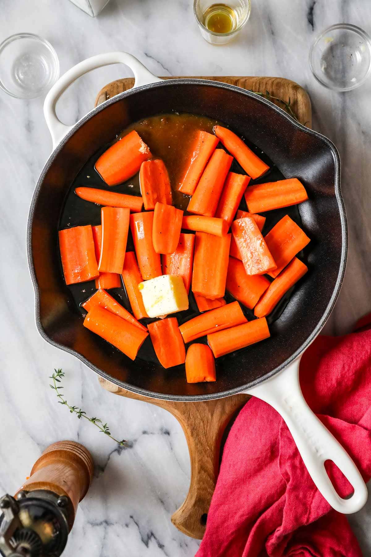 Overhead view of a skillet of carrots cooking in a butter and maple syrup mixture.