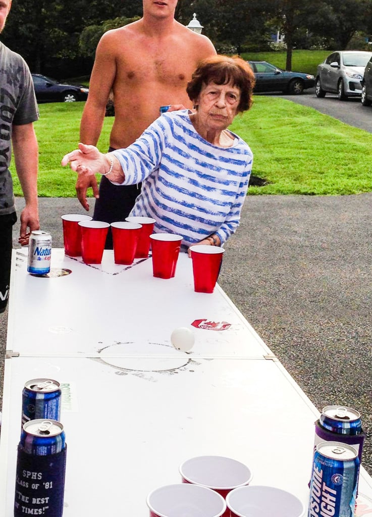 great-grandmother playing beer pong with shirtless college student in background