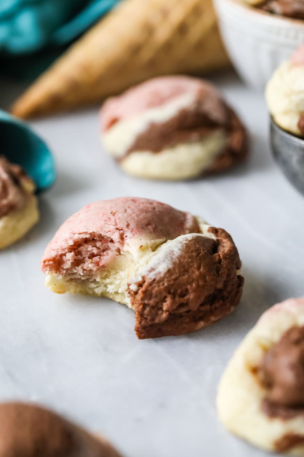 Bite missing from a pink, white, and brown neapolitan cookie.