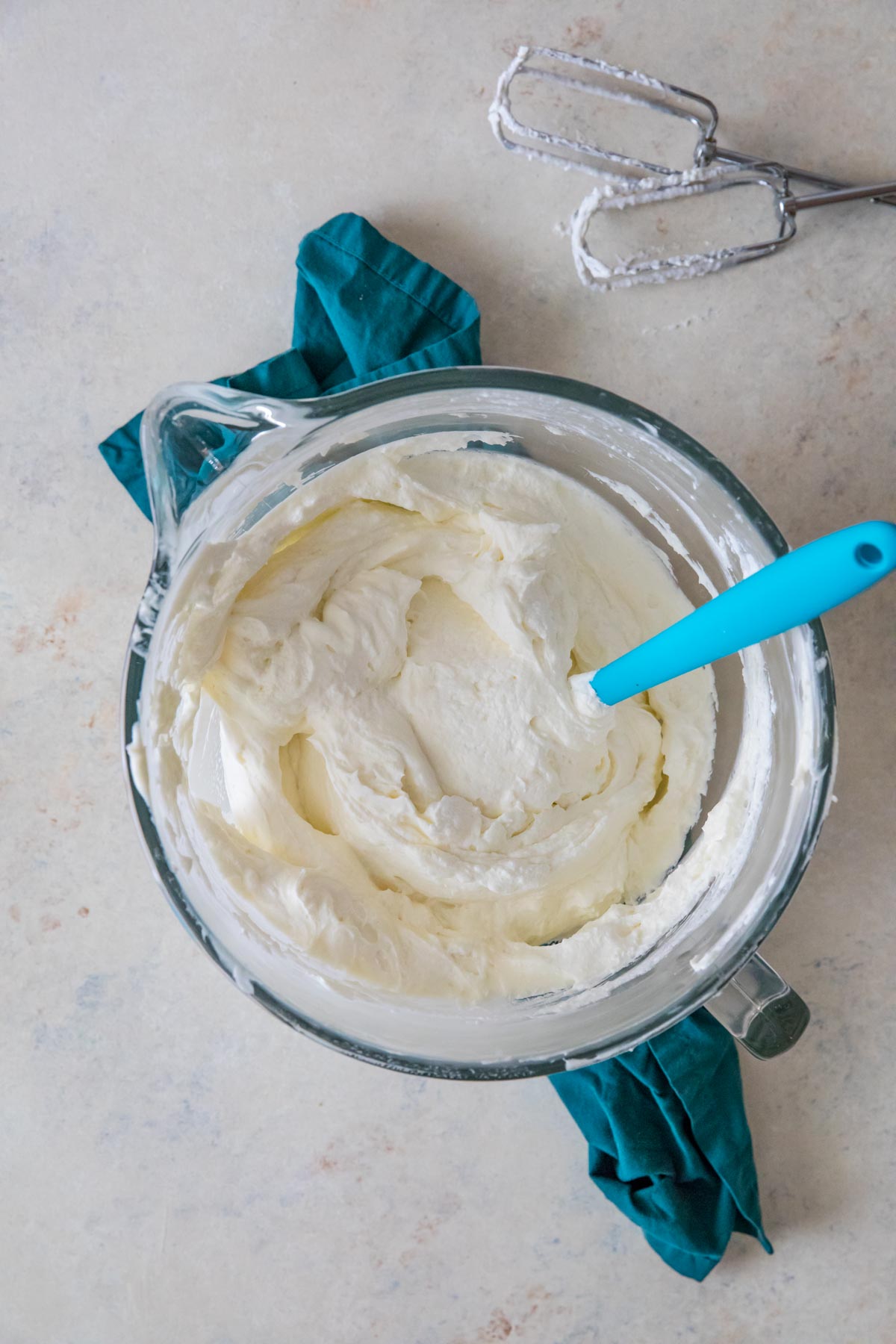 overhead view of cheesecake batter being stirred in a large glass bowl