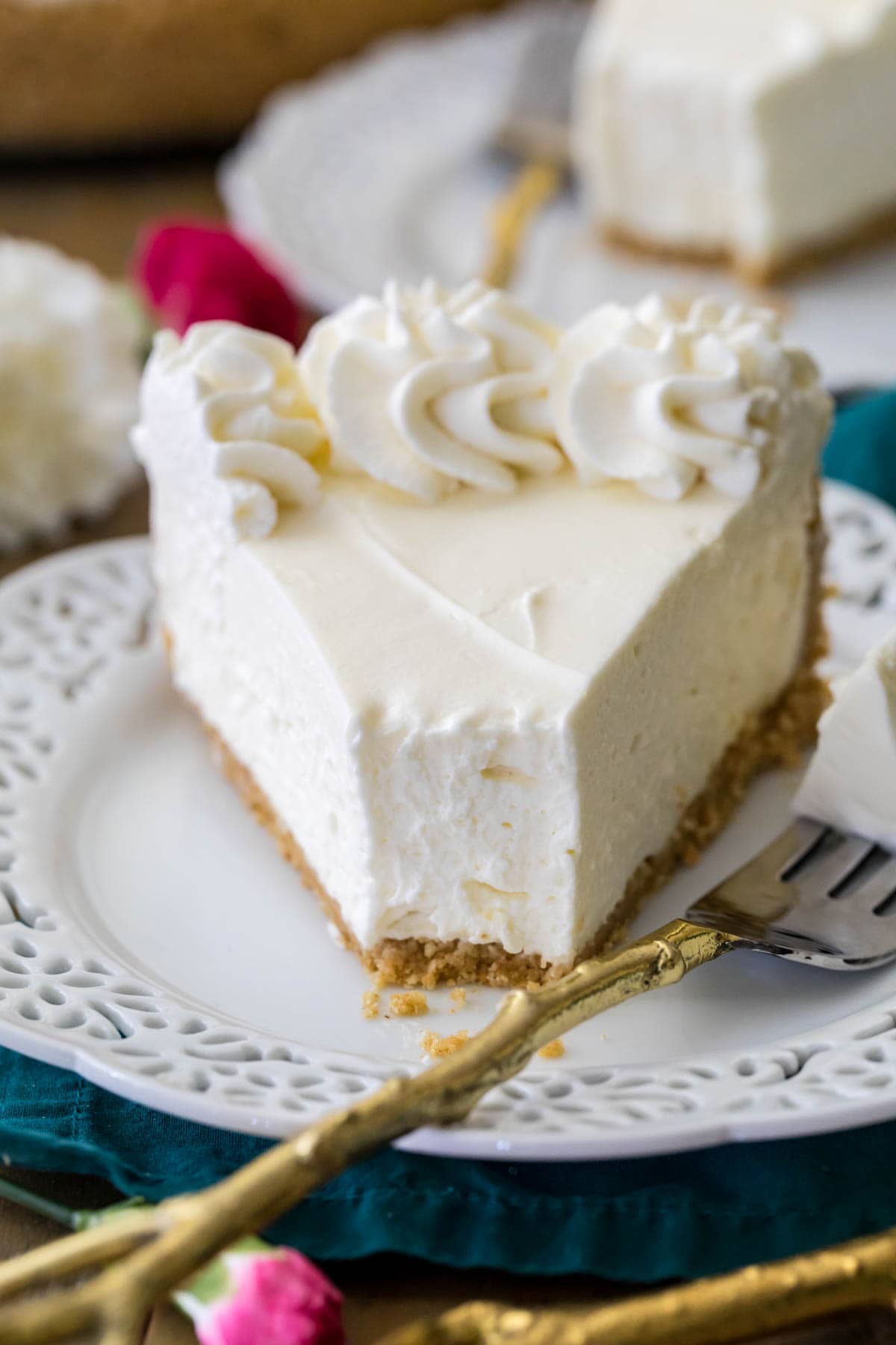 head-on view of a slice of cheesecake missing one bite on a white plate with a fork