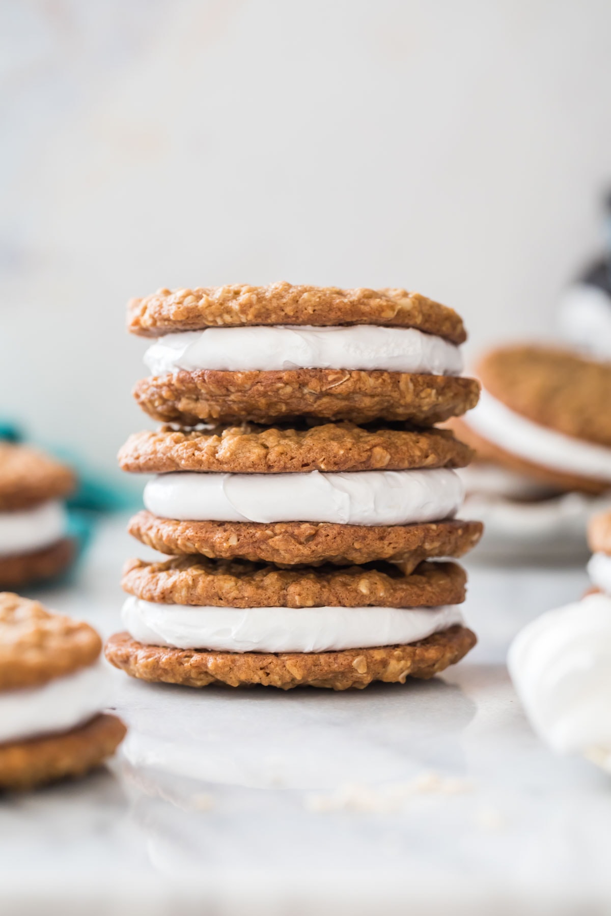three oatmeal cream pies stacked vertically on top of each other with additional cream pies in the foreground and background