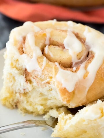 Closeup of orange sweet roll on white plate with a fork
