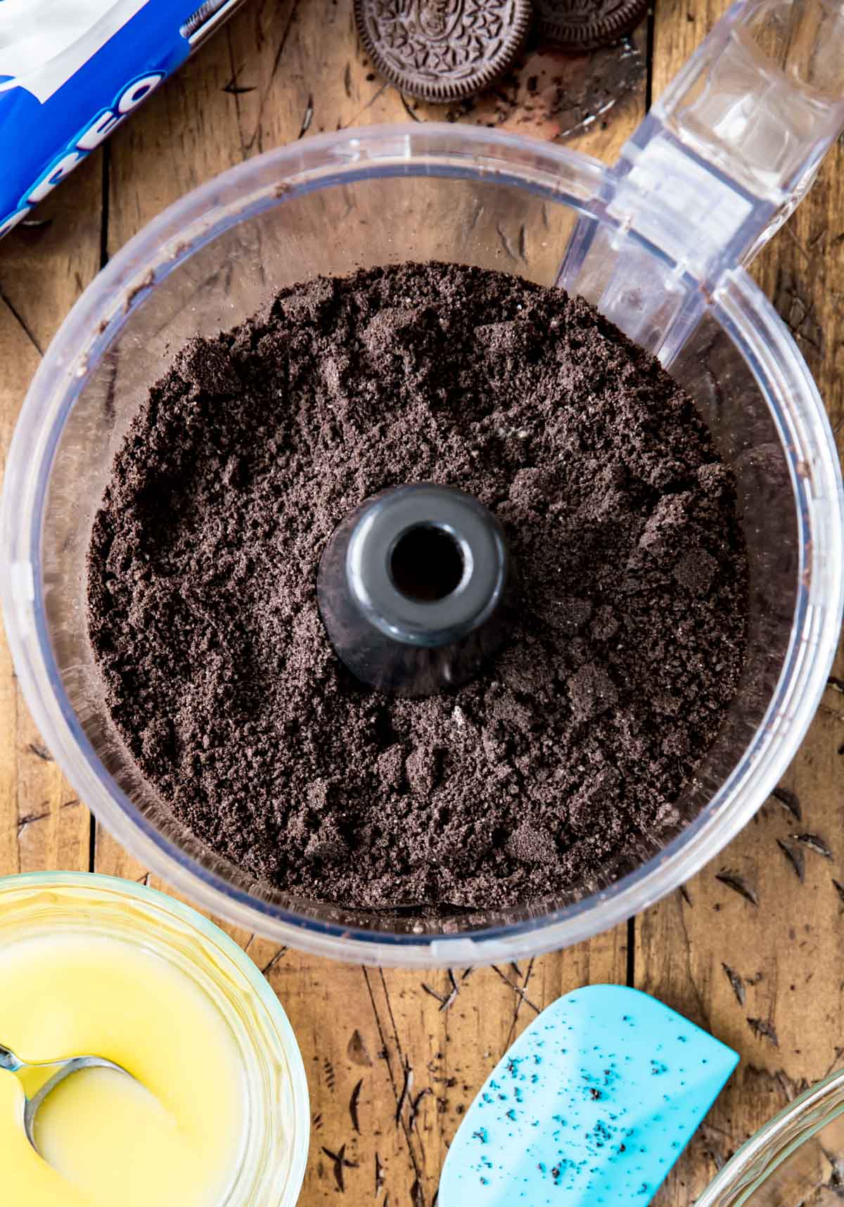 Overhead view of Oreo crumbs in a food processor bowl.