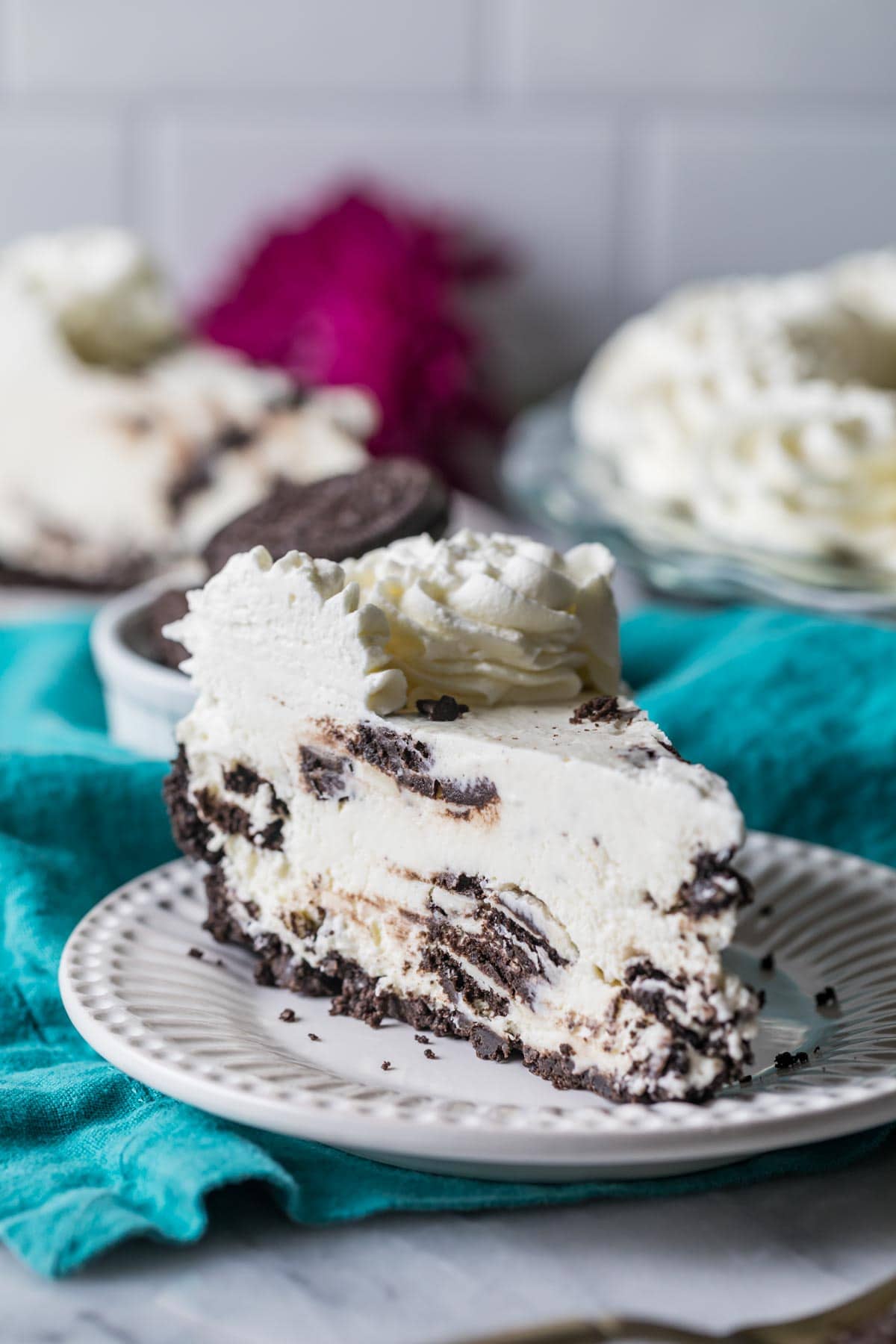 Slice of pie on a plate made with an Oreo crust, Oreo cream filling, and whipped cream topping.