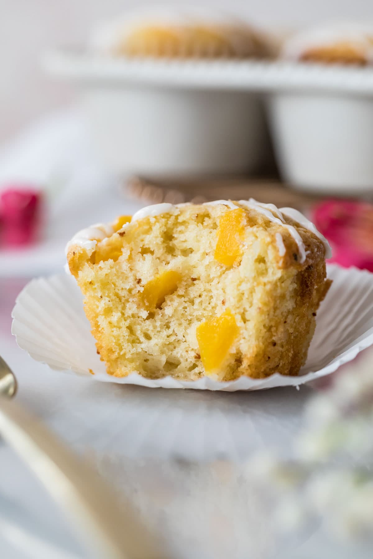 Peach muffin that's been unwrapped and bitten to show fresh peach chunks throughout.