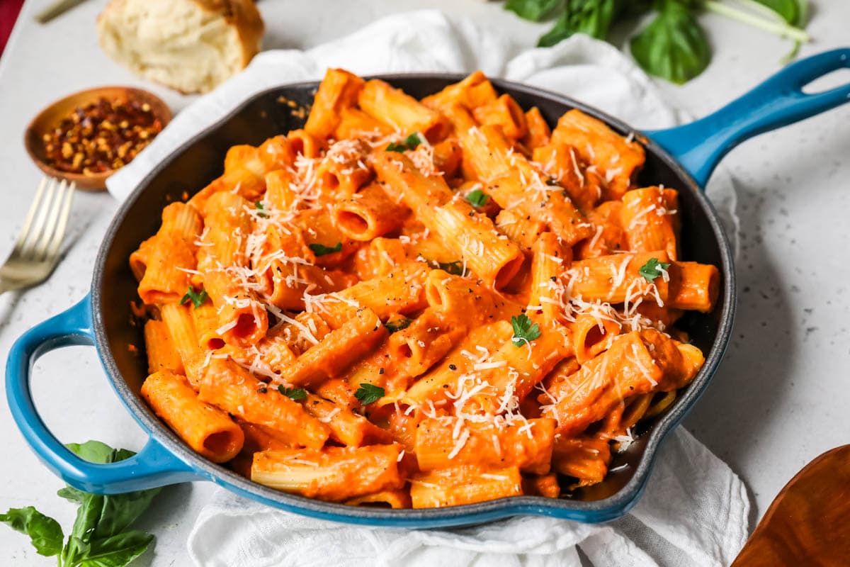 Rigatoni pasta tossed in a tomato cream sauce and served in a blue cast iron skillet.
