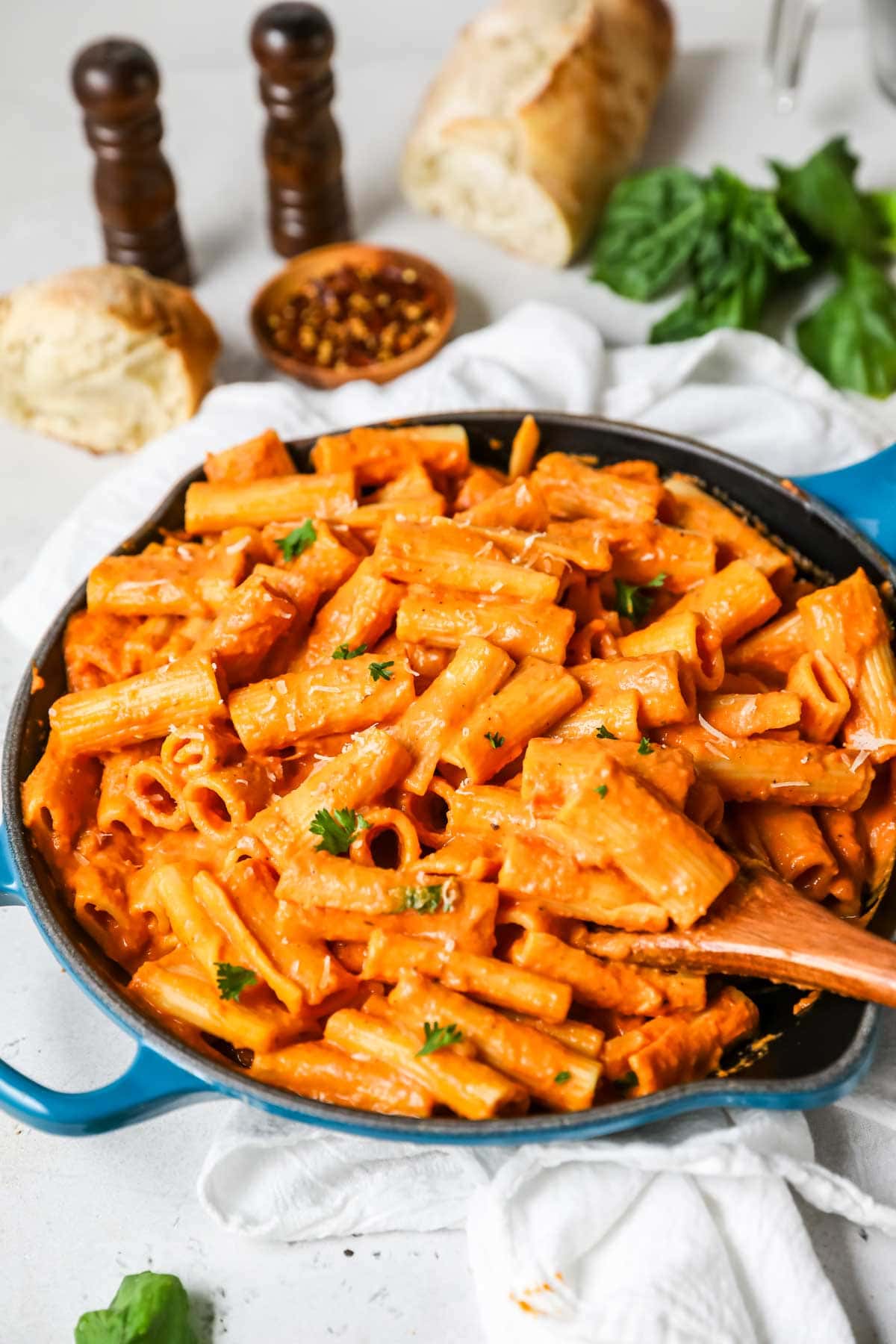 Spoon serving pink sauce pasta from a skillet.