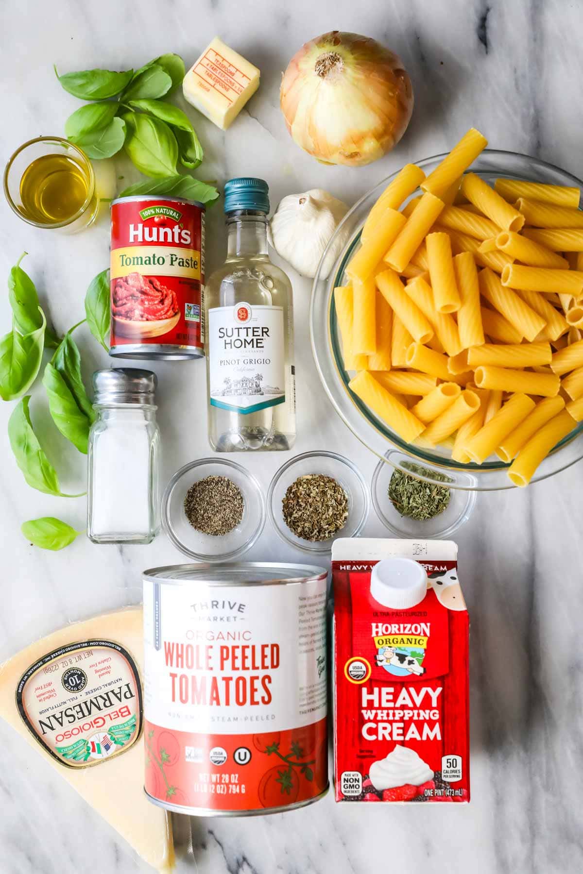 Overhead view of ingredients including pasta, cream, canned tomatoes, and more.