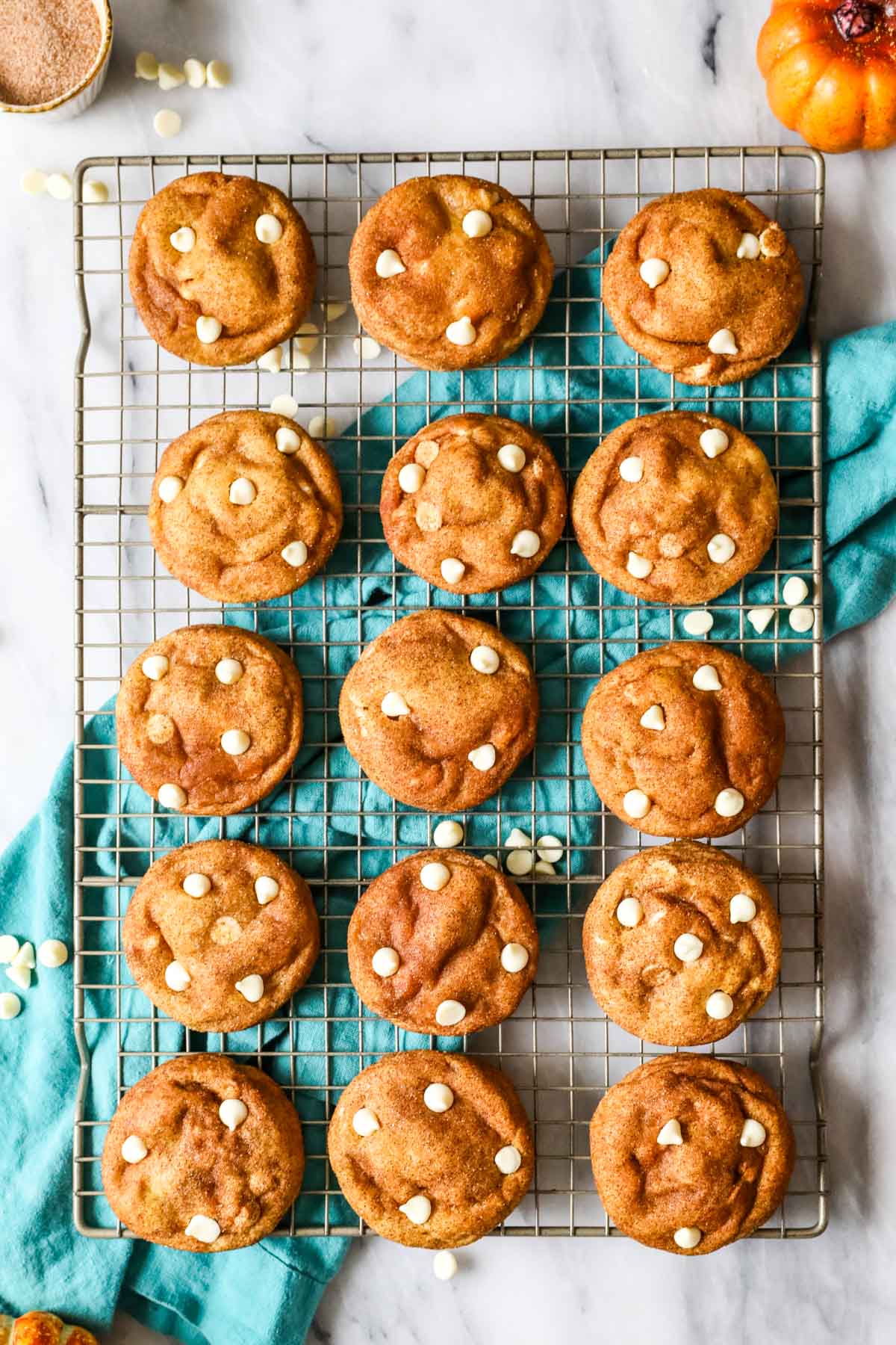 Overhead view of pumpkin cookies with white chocolate chips on a cooling rack.