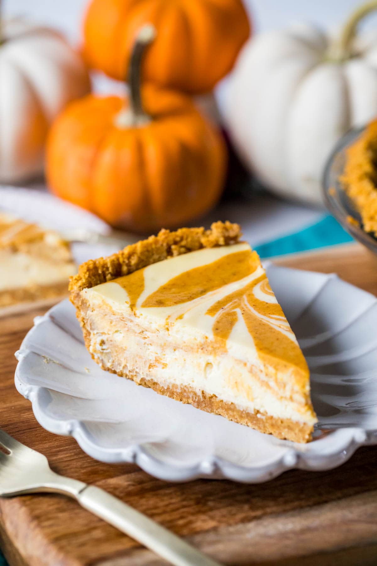 Slice of a swirled pumpkin pie and cheesecake hybrid on a plate.