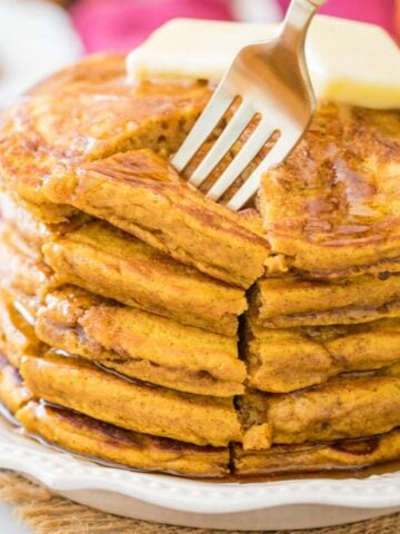 fork piercing a cut section from a stack of thick and fluffy pumpkin pancakes