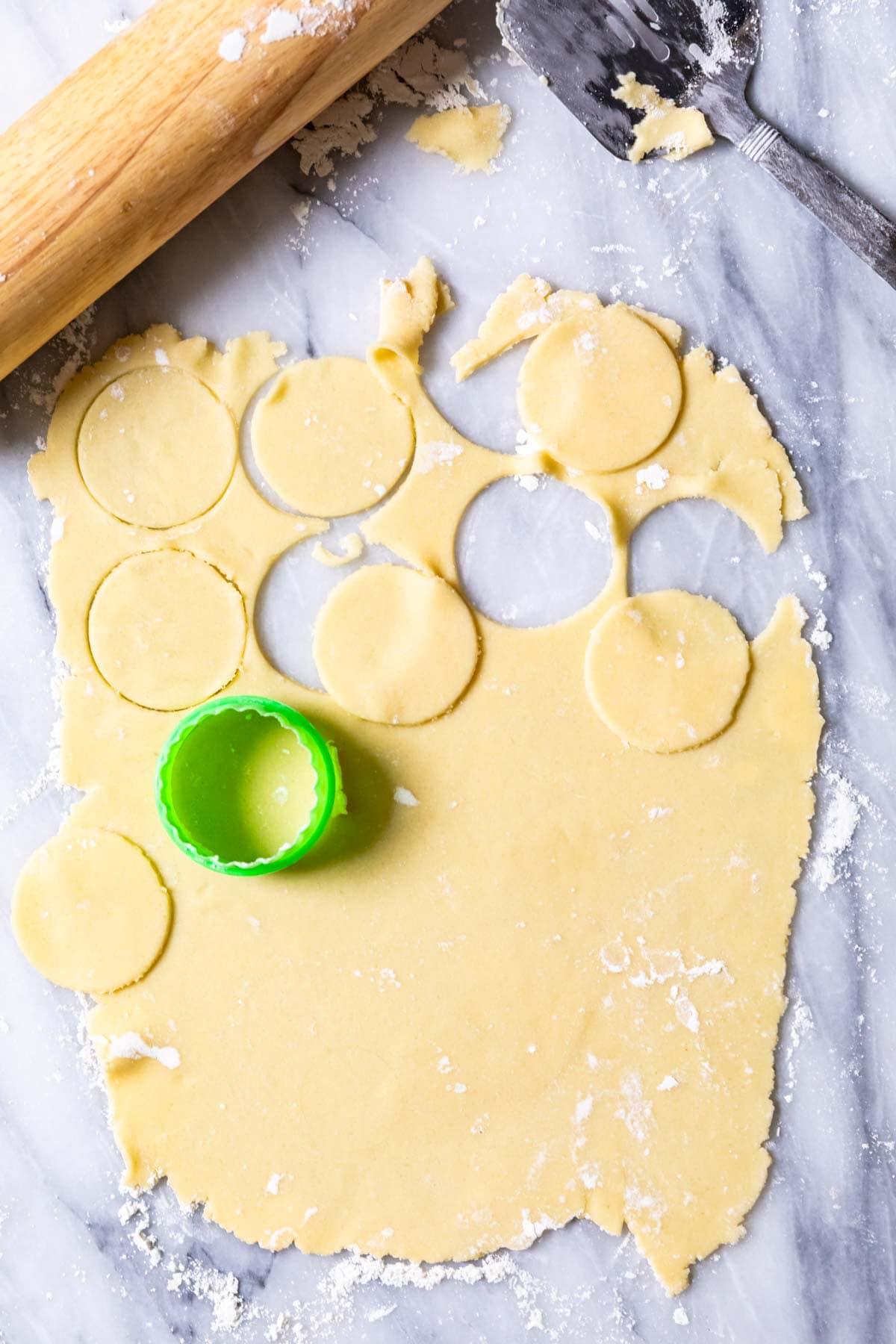 Overhead view of a thin cookie dough being cut into circles.