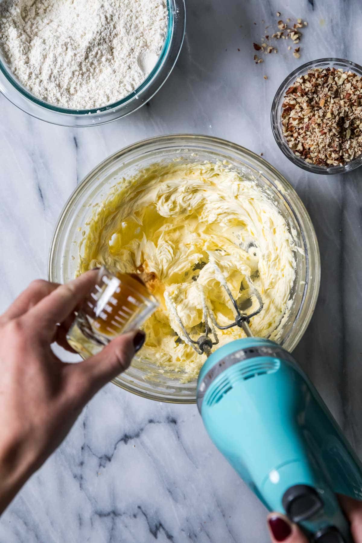 Vanilla extract being added to creamed butter and sugar.