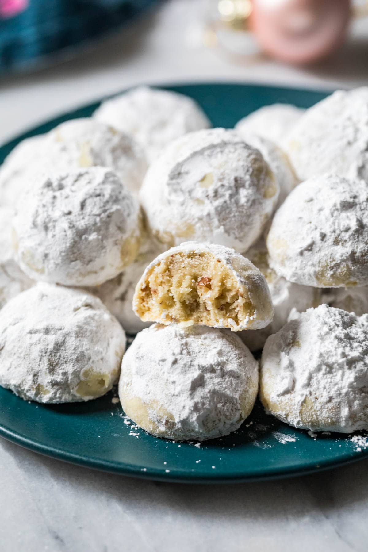 Plate of snowball cookies with one cookie missing a bite.