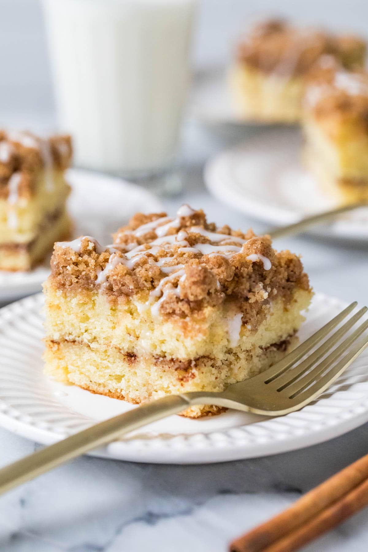 Slice of sour cream coffee cake with a fork on a white plate.