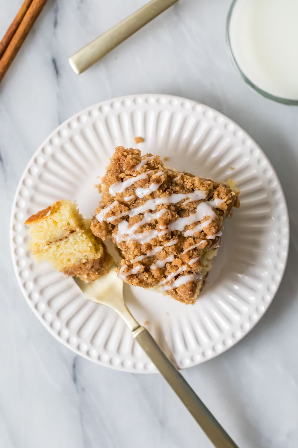 Overhead view of a slice of sour cream coffee cake with one bite on a fork beside the cake.