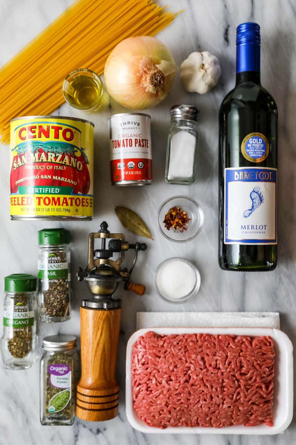 Overhead view of ingredients including red wine, tomatoes, ground beef, and more.