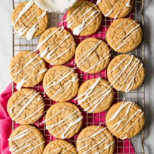 Overhead view of spice cookies topped with a vanilla glaze drizzle on a cooling rack.