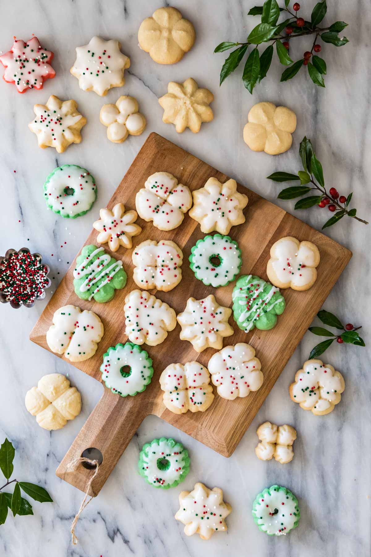 Overhead view of small shaped cookies decorated with vanilla glaze and Christmas sprinkles.