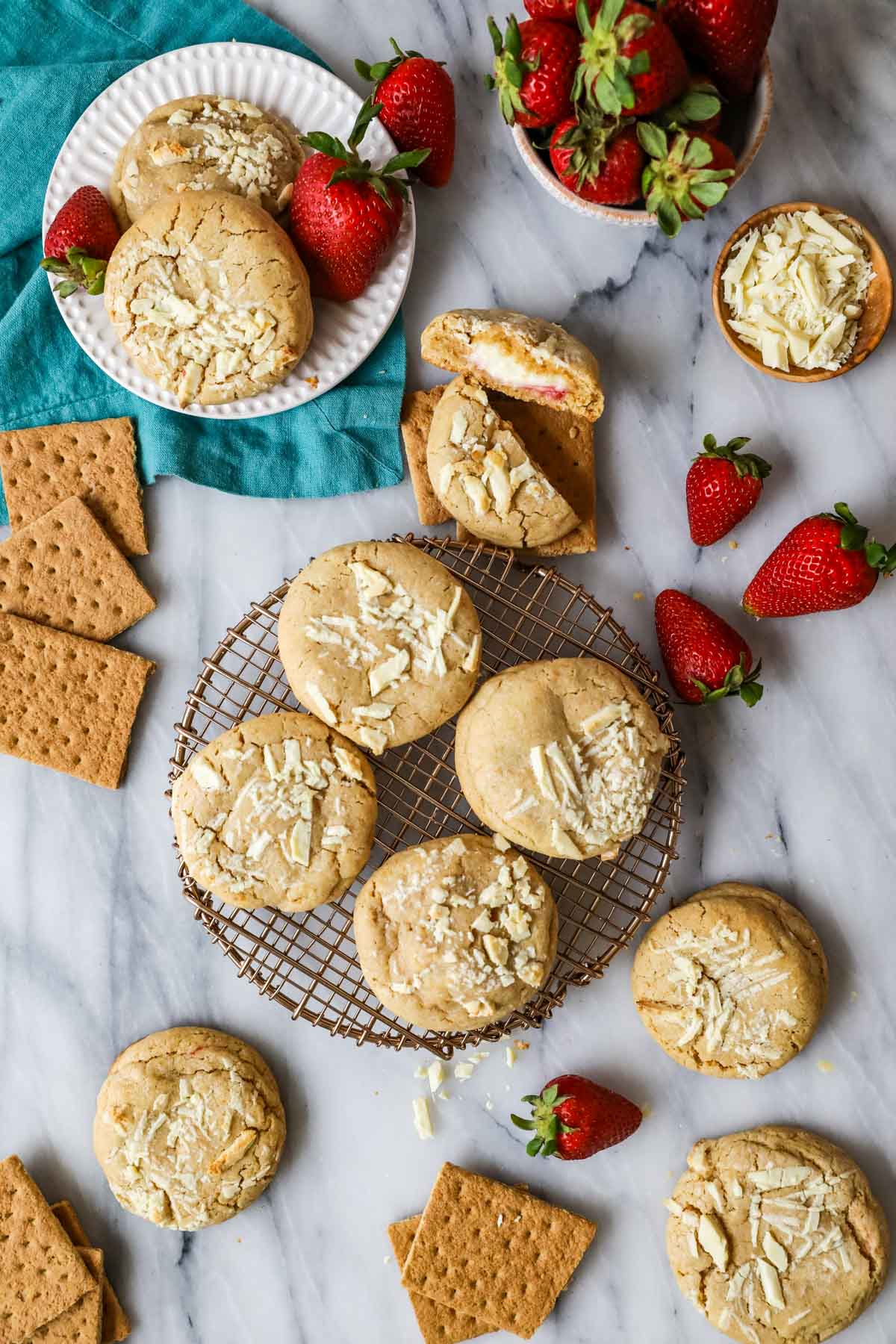 Overhead view of cookies stuffed with cheesecake and strawberry sauce on a metal cooling rack.