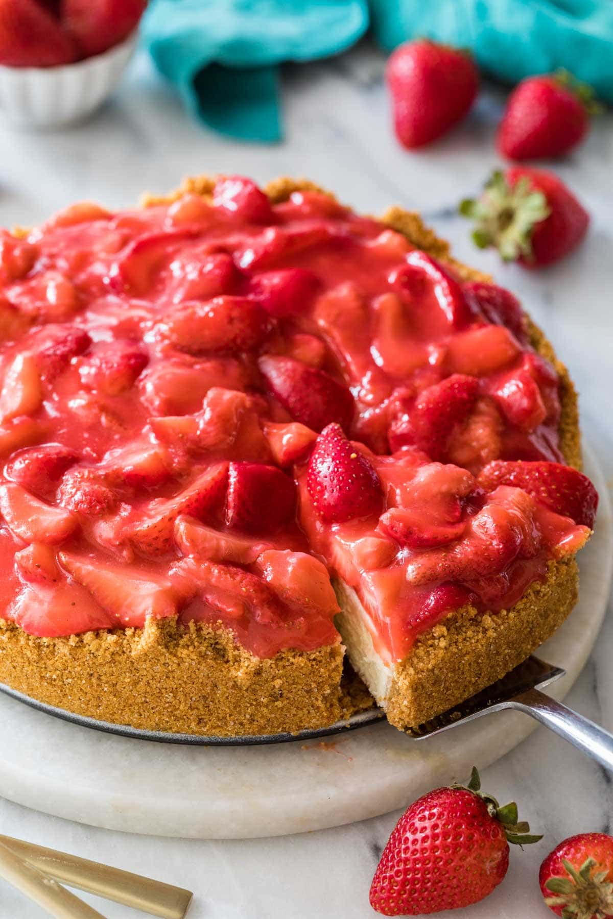 Slice of strawberry cheesecake being served from a serving platter.