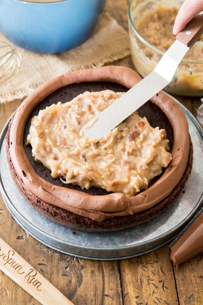 How to assemble German Chocolate Cake: Make a dam around the cake with chocolate frosting and fill with coconut/caramel frosting