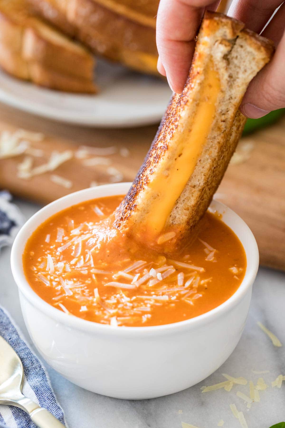 half of a grilled cheese sandwich being dipped into a bowl of tomato soup